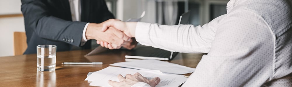 Two men shake hands after a business presentation.