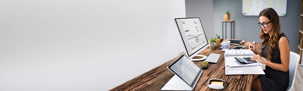 An accountant sits at her desk reviewing an invoice.