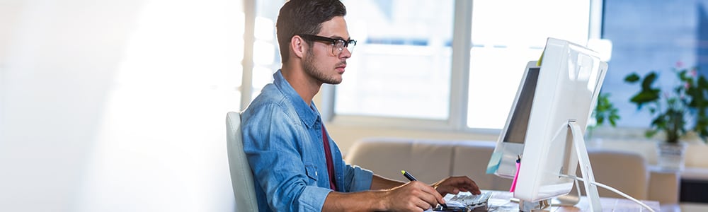 A chiropractor looks at a computer monitor as he works on his practice logo.