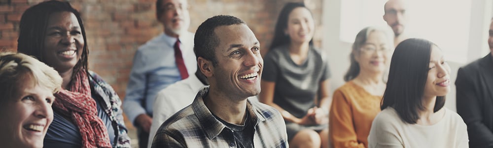 A group of people is watching something offscreen and smiling.