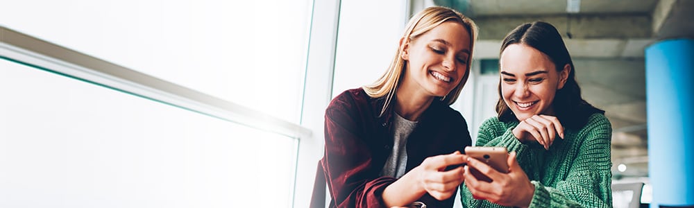 2 woman looking at social media on phone