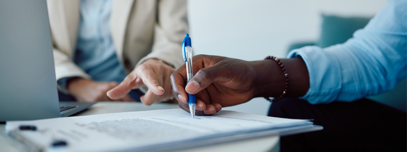 Hand holding pen on stack of papers